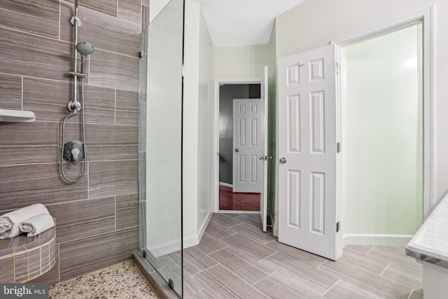 full bath with tiled shower and baseboards