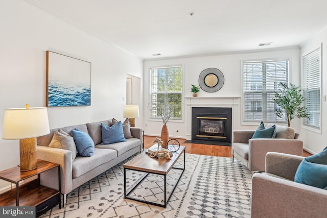 living room with a wealth of natural light, a fireplace with flush hearth, visible vents, and wood finished floors