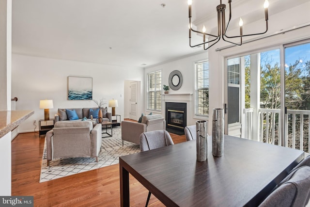 dining room featuring a notable chandelier, ornamental molding, wood finished floors, and a glass covered fireplace