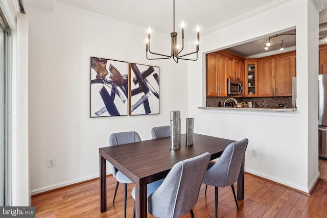 dining space with light wood-style flooring, baseboards, and crown molding