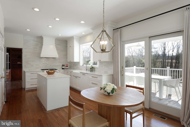 kitchen featuring dark wood-style floors, tasteful backsplash, a center island, and custom range hood