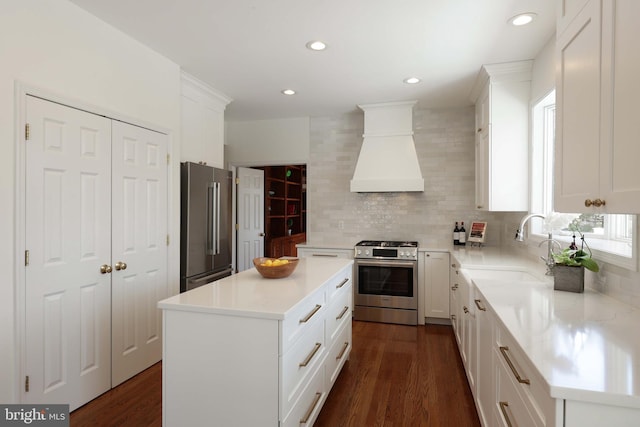 kitchen featuring a kitchen island, custom range hood, appliances with stainless steel finishes, a sink, and backsplash