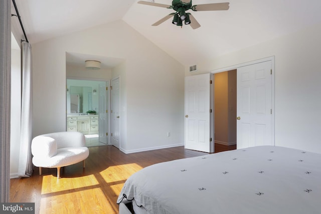 bedroom with high vaulted ceiling, wood finished floors, visible vents, baseboards, and ensuite bath