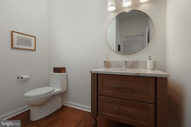 bathroom with baseboards, vanity, toilet, and wood finished floors