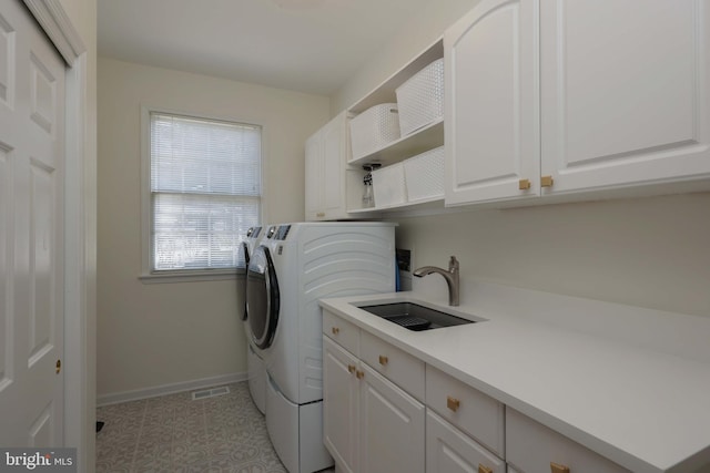 laundry room featuring cabinet space, baseboards, visible vents, independent washer and dryer, and a sink