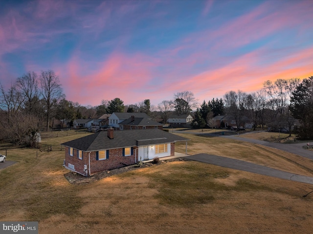 view of front facade with driveway, brick siding, a front yard, and fence