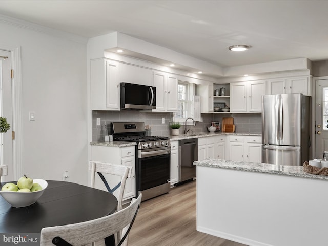 kitchen featuring a sink, stainless steel appliances, open shelves, and white cabinetry