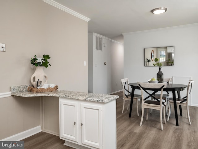 dining space with dark wood-type flooring and crown molding