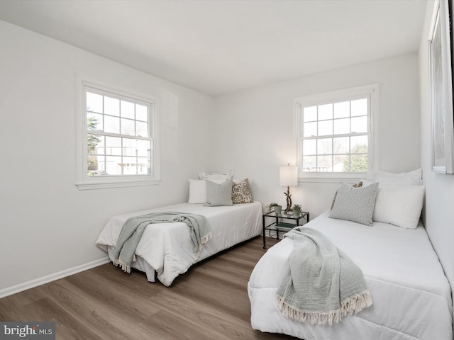 bedroom featuring multiple windows, wood finished floors, and baseboards