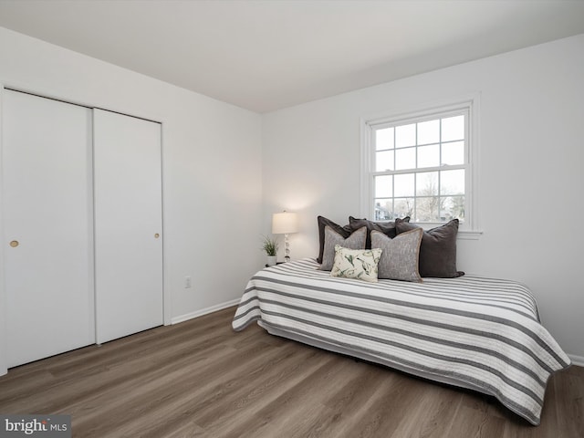 bedroom with wood finished floors, a closet, and baseboards