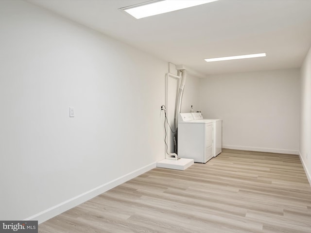 clothes washing area featuring laundry area, washer and dryer, light wood-type flooring, and baseboards