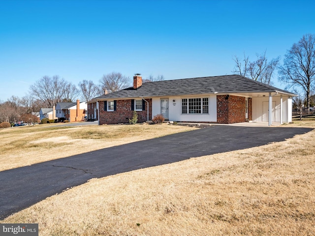 single story home featuring an attached carport, brick siding, a chimney, and driveway