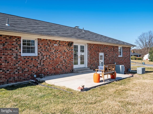 rear view of house with brick siding, central air condition unit, french doors, a yard, and a patio area