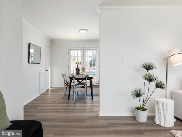 dining room with crown molding, wood finished floors, and baseboards