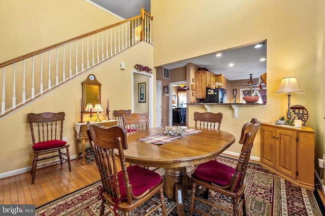 dining area with stairway, baseboards, visible vents, and hardwood / wood-style floors