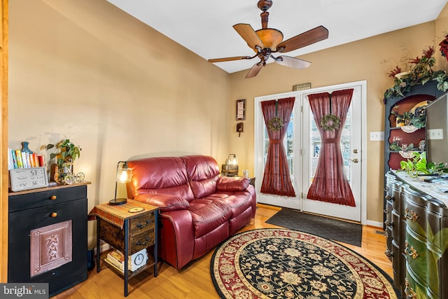 living room featuring baseboards, light wood-style floors, and a ceiling fan