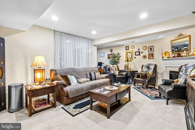 living room with a glass covered fireplace, recessed lighting, and light colored carpet