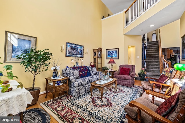 living area featuring stairway, baseboards, wood finished floors, and a towering ceiling