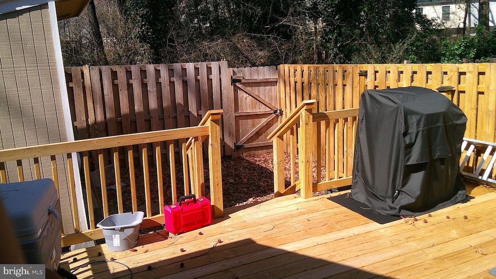 wooden deck with grilling area, fence, and a gate