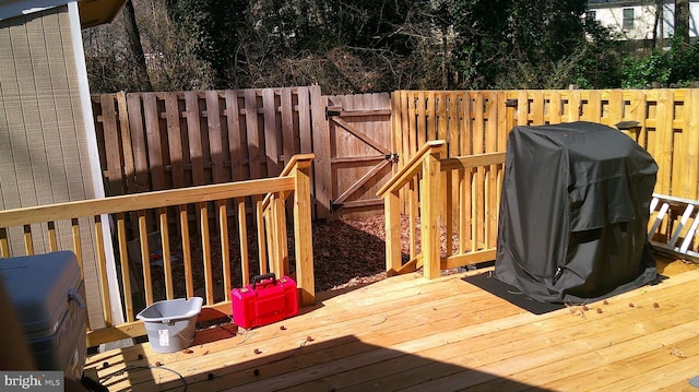 wooden deck with grilling area, fence, and a gate