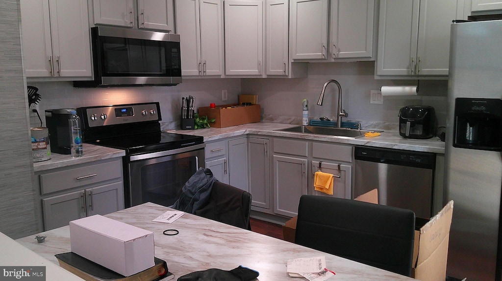 kitchen with light countertops, gray cabinetry, appliances with stainless steel finishes, and a sink