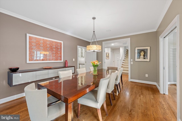 dining space with baseboards, light wood-style flooring, and ornamental molding