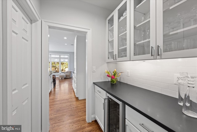 bar featuring wine cooler, wood finished floors, and tasteful backsplash