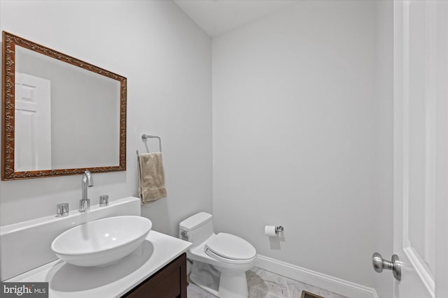 half bath with vanity, toilet, baseboards, and marble finish floor