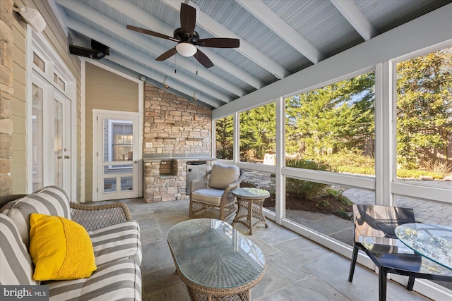 sunroom featuring a ceiling fan and vaulted ceiling with beams