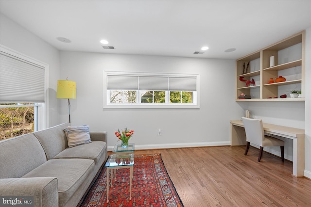 living area with visible vents, a healthy amount of sunlight, light wood-type flooring, and baseboards