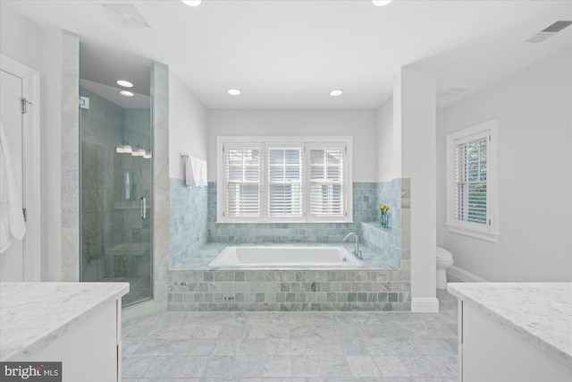 bathroom with vanity, toilet, a bath, and a stall shower