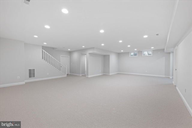 basement featuring visible vents, baseboards, recessed lighting, stairs, and light colored carpet