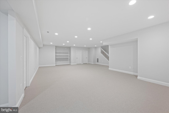 finished basement featuring light colored carpet, stairway, recessed lighting, and baseboards