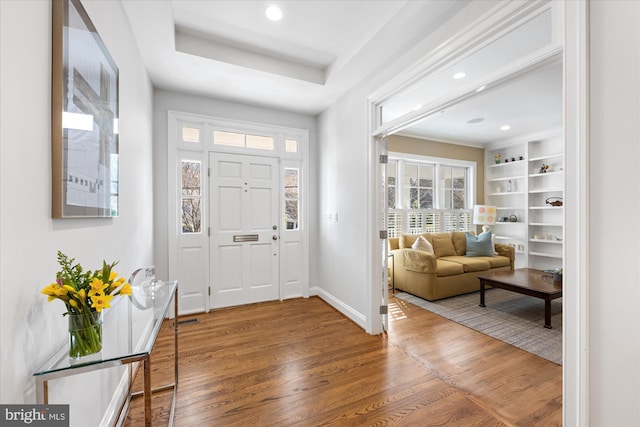 entrance foyer with recessed lighting, a raised ceiling, baseboards, and wood finished floors