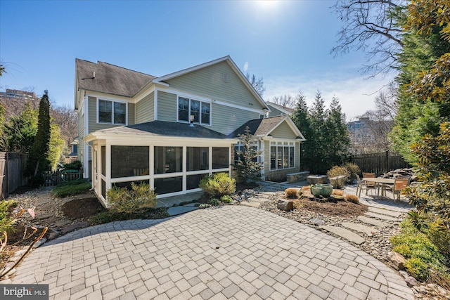 back of property featuring a patio area, fence, and a sunroom