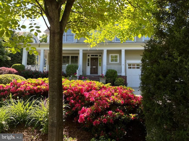 view of front of home featuring brick siding, a porch, and a garage