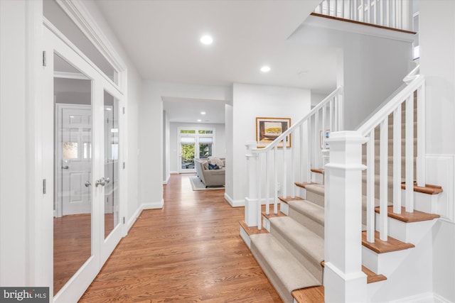 foyer entrance featuring wood finished floors, baseboards, recessed lighting, stairs, and french doors