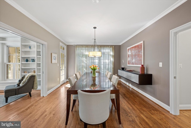 dining room featuring a chandelier, baseboards, wood finished floors, and crown molding