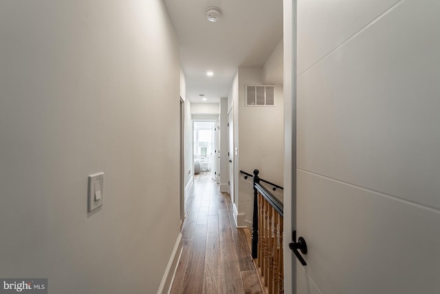 hallway featuring wood finished floors, visible vents, and baseboards