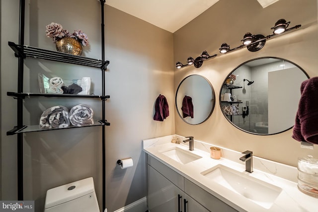 full bath featuring a sink, a tile shower, toilet, and double vanity