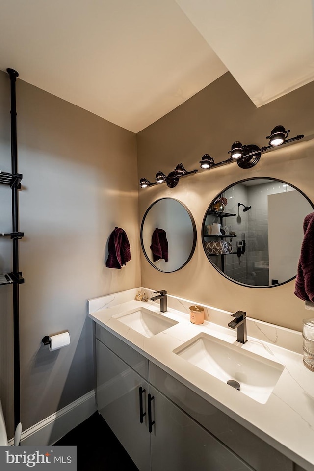 full bathroom featuring double vanity, baseboards, and a sink