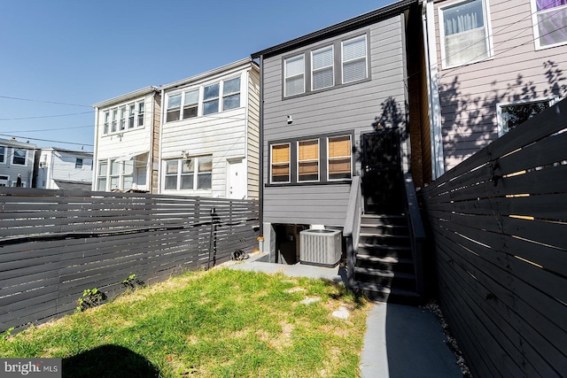 rear view of house with entry steps, fence, and central AC unit