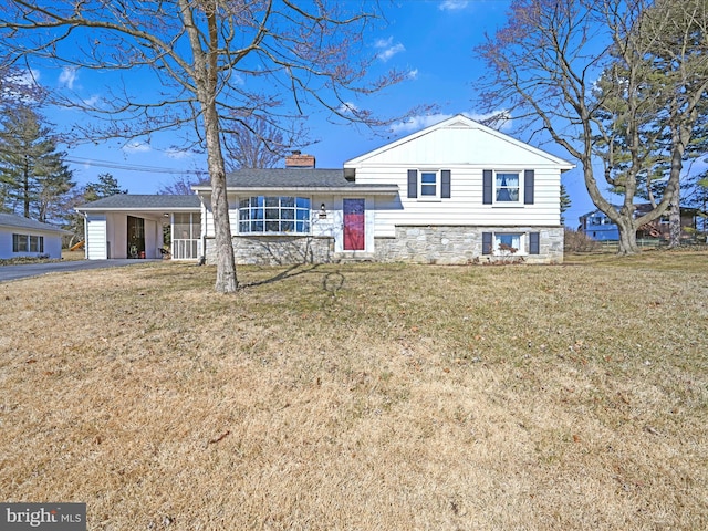 tri-level home with driveway, a front lawn, a chimney, and stone siding