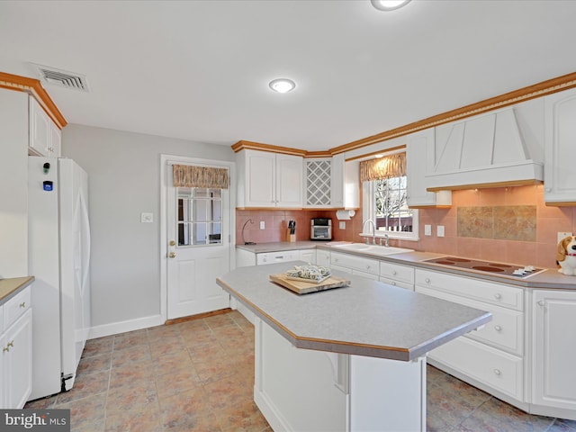 kitchen with freestanding refrigerator, a sink, custom exhaust hood, electric stovetop, and backsplash