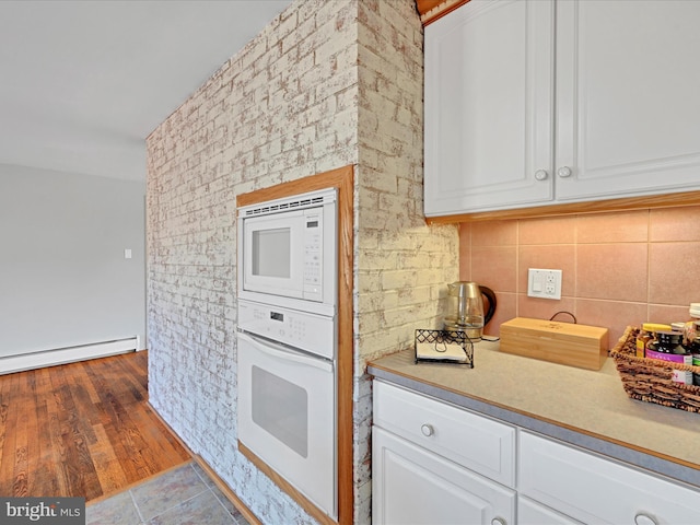 kitchen with white appliances, white cabinetry, decorative backsplash, and light countertops