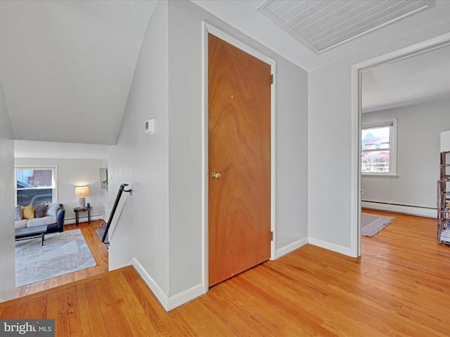 hallway featuring visible vents, baseboards, a baseboard radiator, an upstairs landing, and light wood-style floors