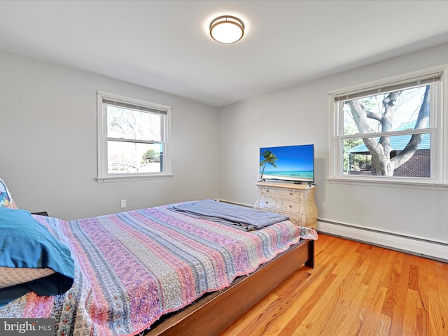 bedroom with baseboard heating and light wood-type flooring