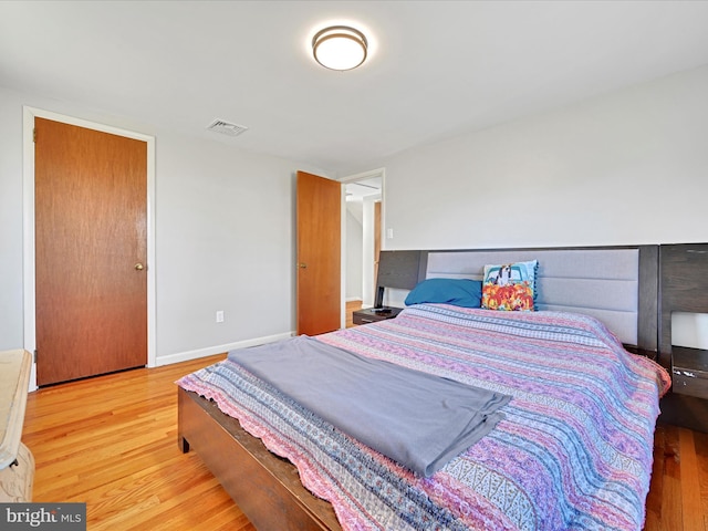 bedroom with baseboards, visible vents, and wood finished floors