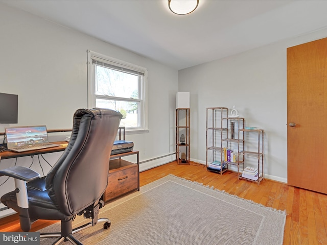 office area with wood-type flooring, a baseboard heating unit, and baseboards