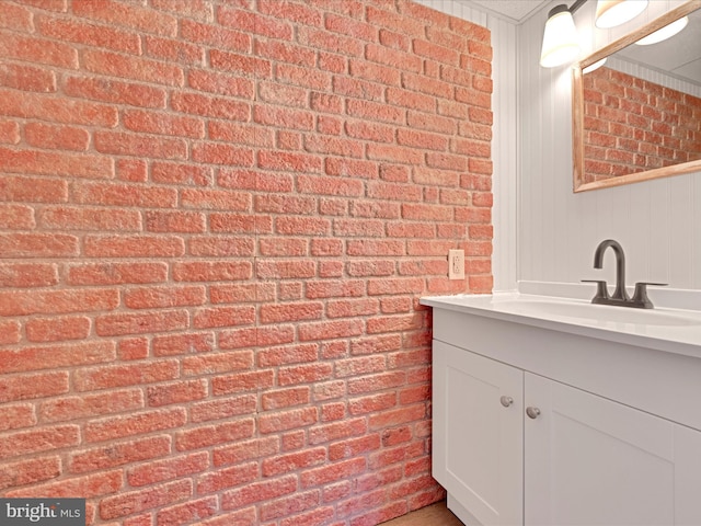 bathroom featuring brick wall and vanity